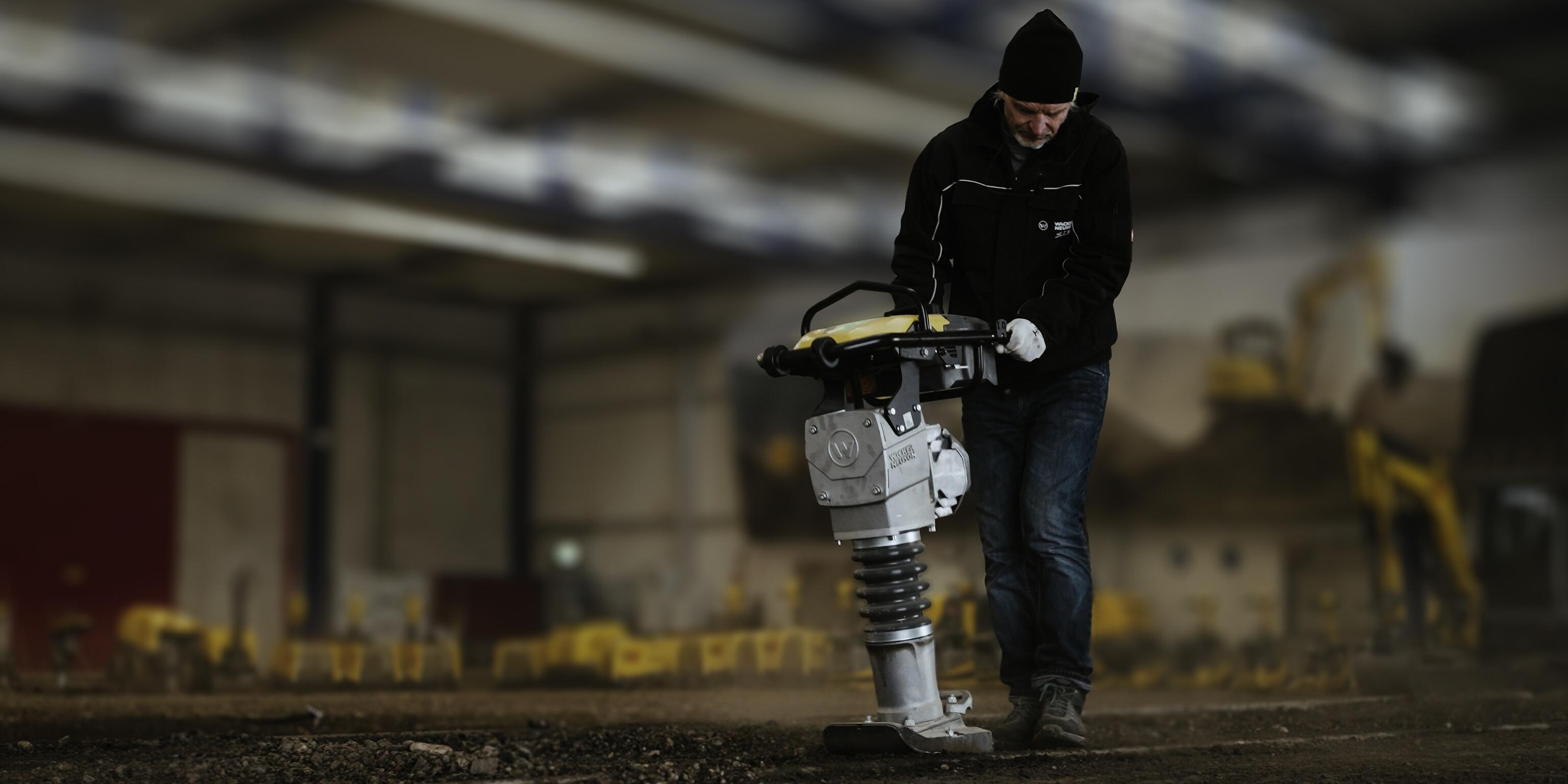 Worker operating rammer for soil compaction in indoor construction training environment
