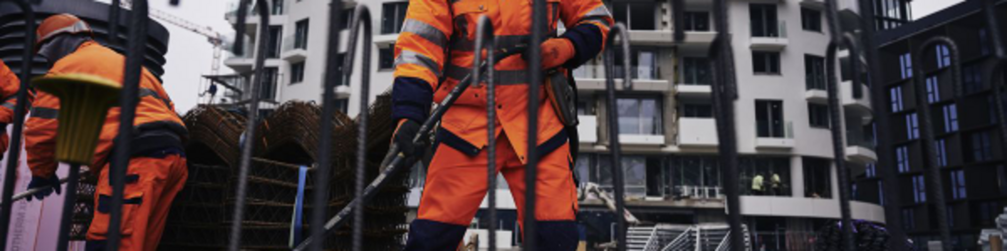 Construction worker on a construction site compacting concrete with a Wacker Neuson internal vibrator.