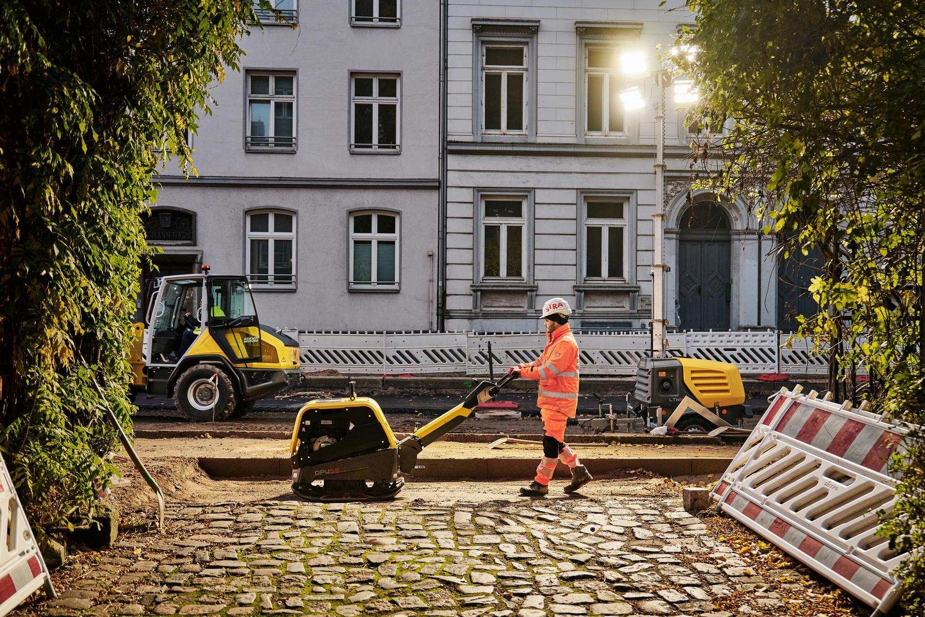 Man working with dumper on road with old expensive houses in the background